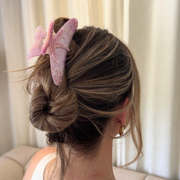Woman with light brown hair in a messy bun, wearing a pink starfish-shaped claw clip from Coconut Lane.