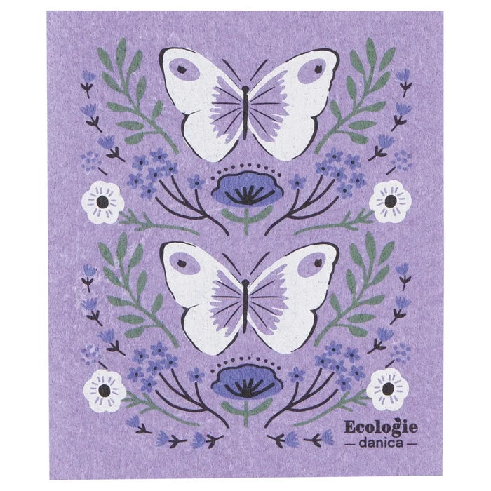 Swedish dishcloth with lavender background featuring two large white butterflies with light purple wing details, surrounded by green leaves, small blue flowers, and a few white blossoms.