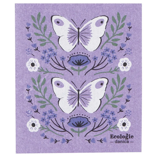 Swedish dishcloth with lavender background featuring two large white butterflies with light purple wing details, surrounded by green leaves, small blue flowers, and a few white blossoms.