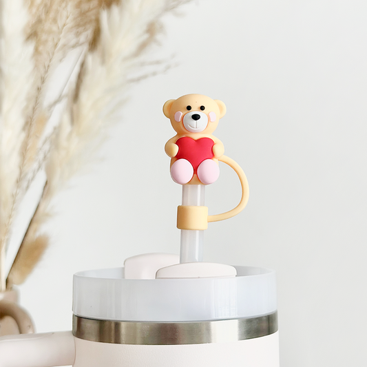 Light brown Teddy Love straw cover by Coconut Lane on a travel cup, pampas grass blurred in the background.