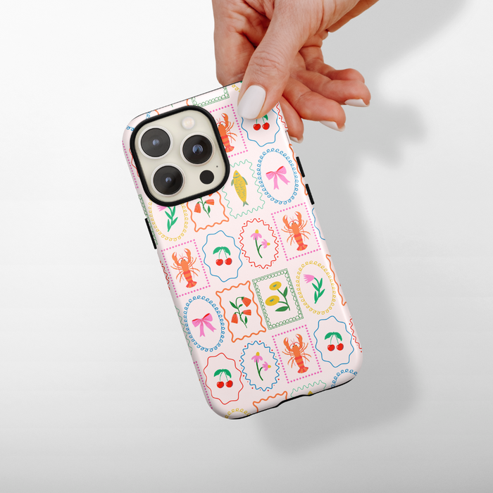 Coconut Lane Tough MagSafe® phone case with playful lobster, flower, bow, and leaf pattern held in hand.