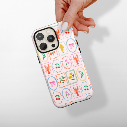 Coconut Lane Tough MagSafe® phone case with playful lobster, flower, bow, and leaf pattern held in hand.