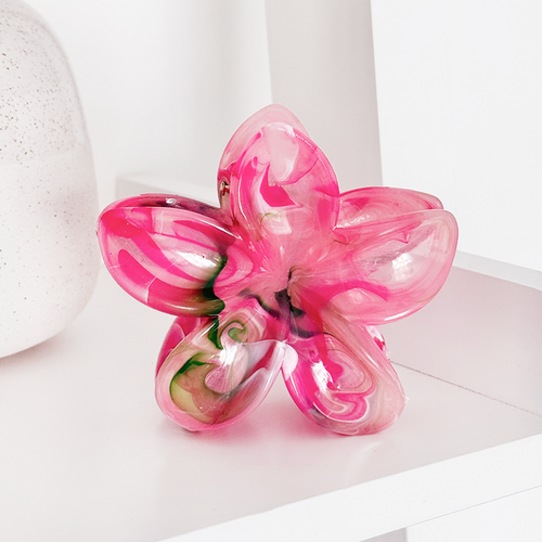 Tropical flower-pattern claw clip with pastel colors on a shelf beside a textured ceramic vase.