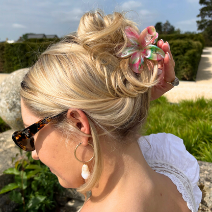 Blonde woman with hair in an updo wears a Coconut Lane floral-patterned claw clip outside on a sunny day.