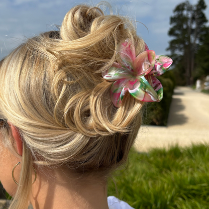 Blonde hair in a messy bun secured with a floral-patterned claw clip from Coconut Lane, outdoors on a sunny day.