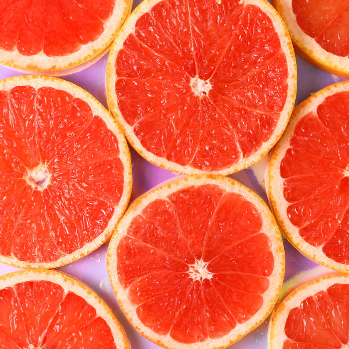 Sliced grapefruits arranged on a purple background