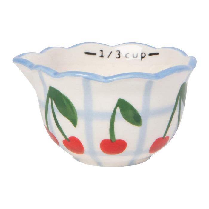 Small ceramic measuring cup with cherry design on a white background