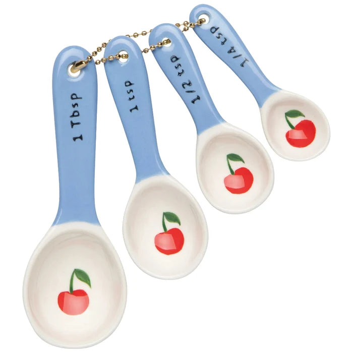 Set of four ceramic measuring spoons with cherry design on a white background